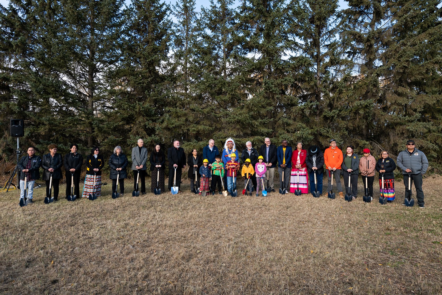 Several people stand together on an empty field as part of a groundbreaking ceremony.