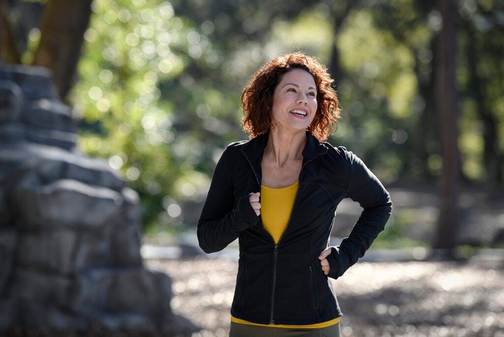 White woman with wavy hair smiling and running