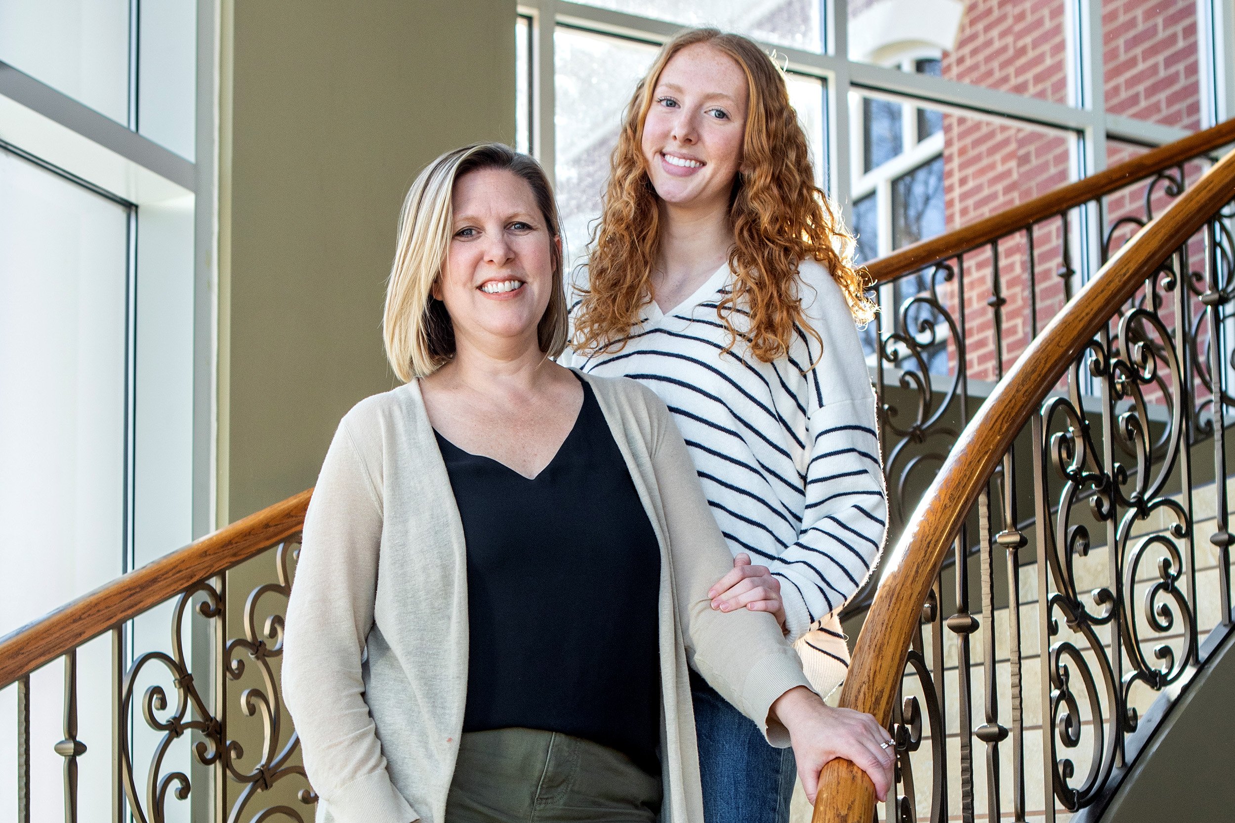 Two women, one blonde and one red-headed, smiling towards camera.