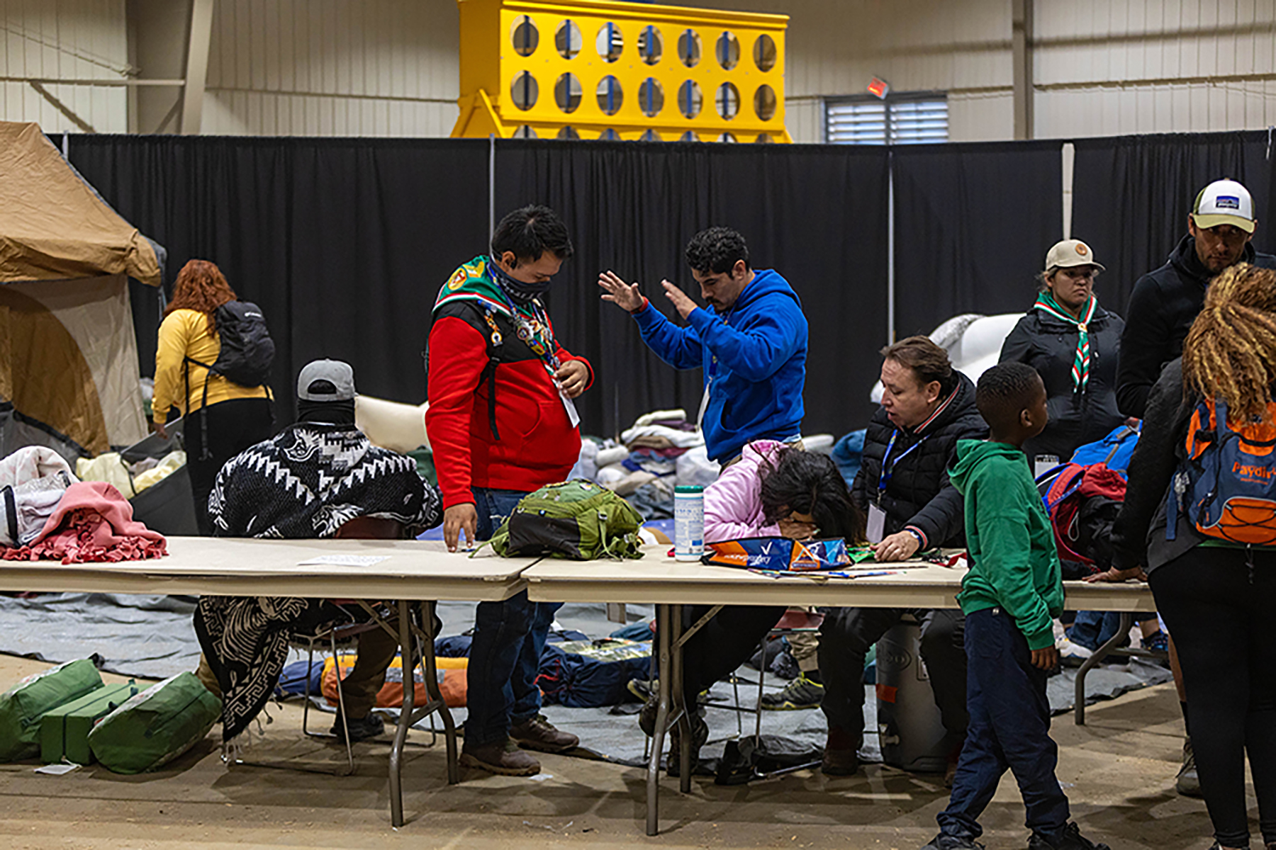 A photo of a donation drop-off center for camping supplies with several volunteers and visitors pictured.