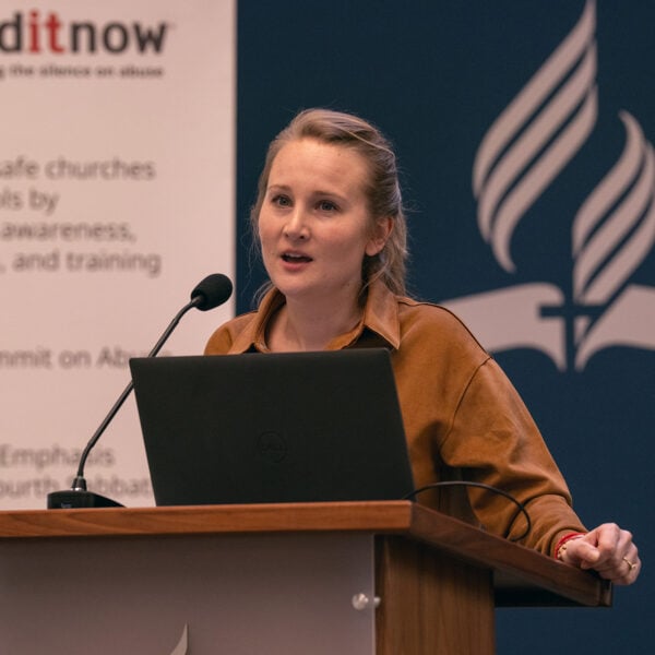White woman speaks at a podium in front of an enditnow poster.