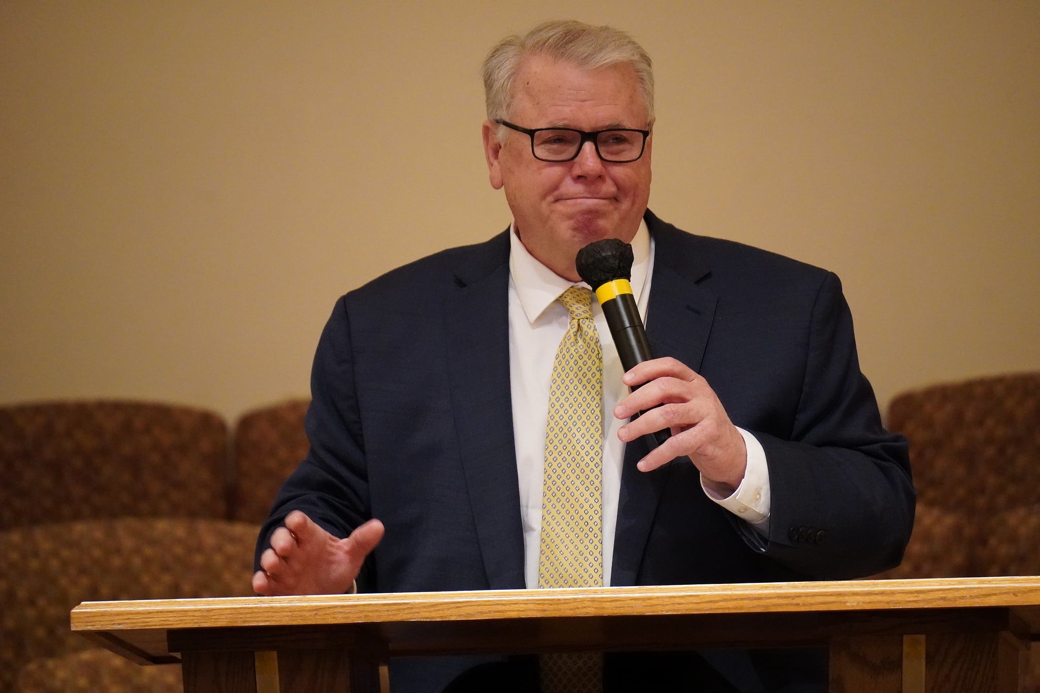Caucasian middle aged man with glasses and gray hair speaks at a church setting