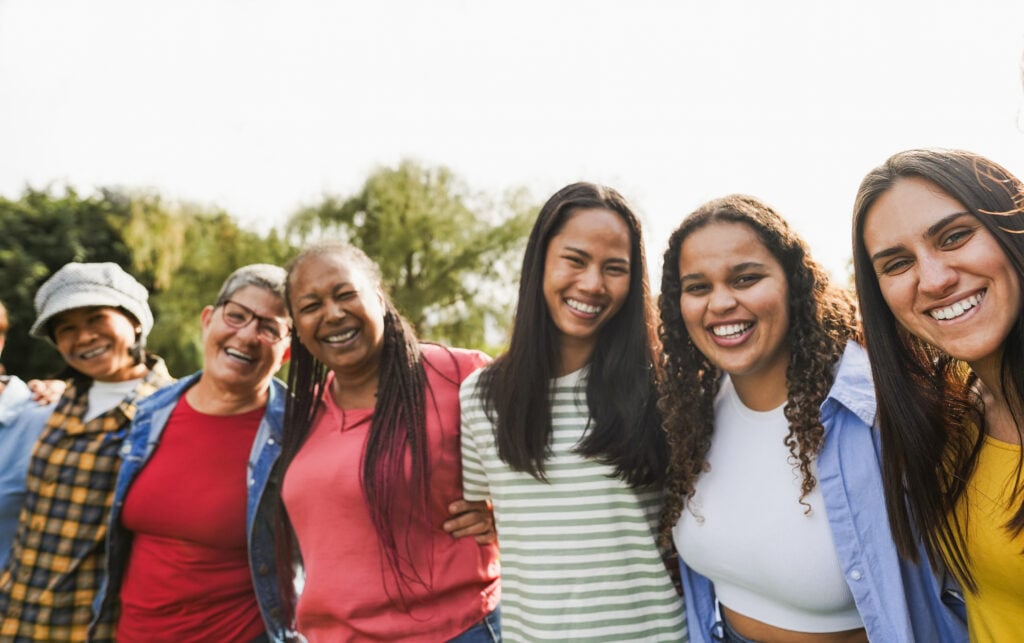 Multi generational women with arms around each other's shoulders together outdoors