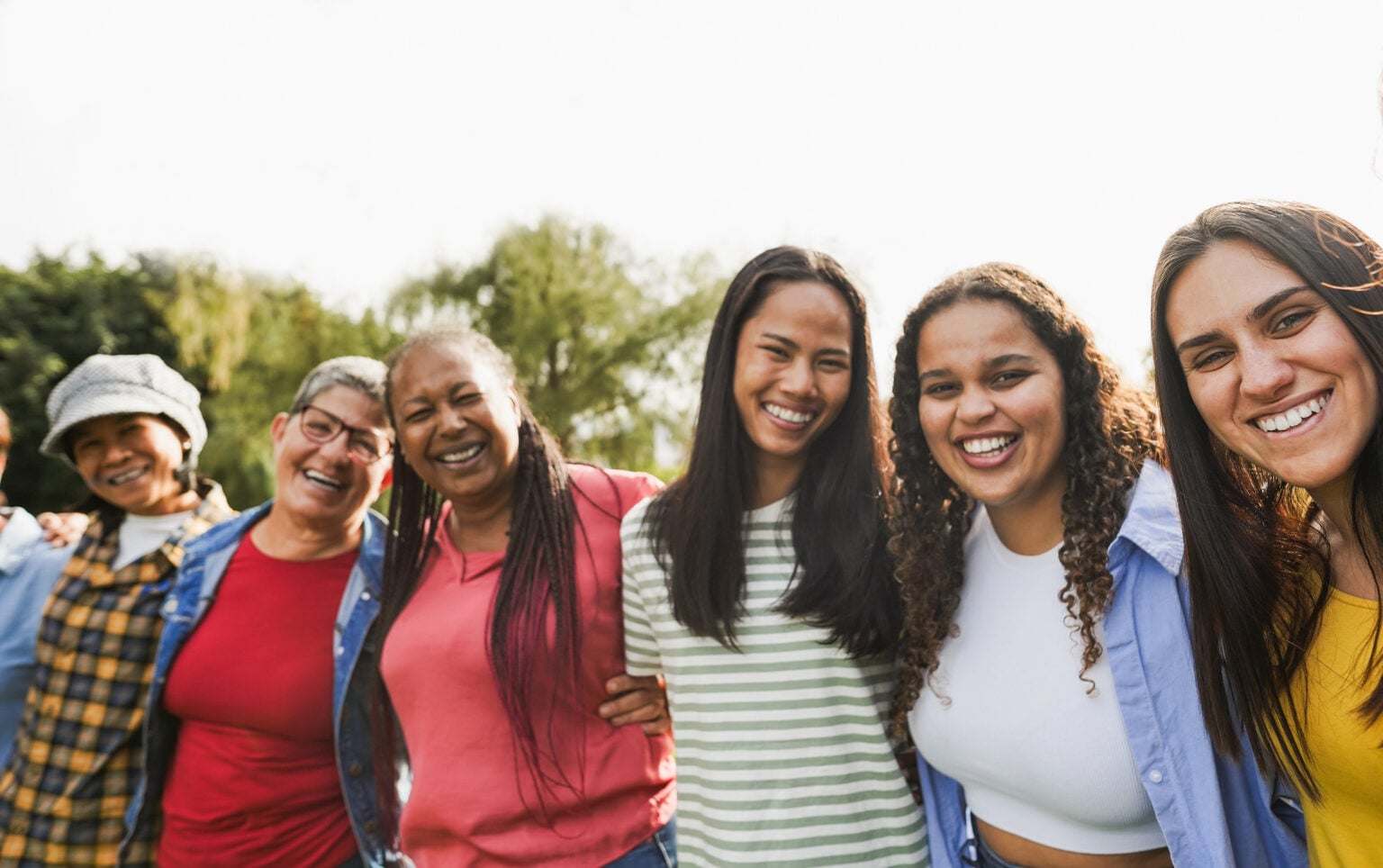 Multi generational women with arms around each other's shoulders together outdoors