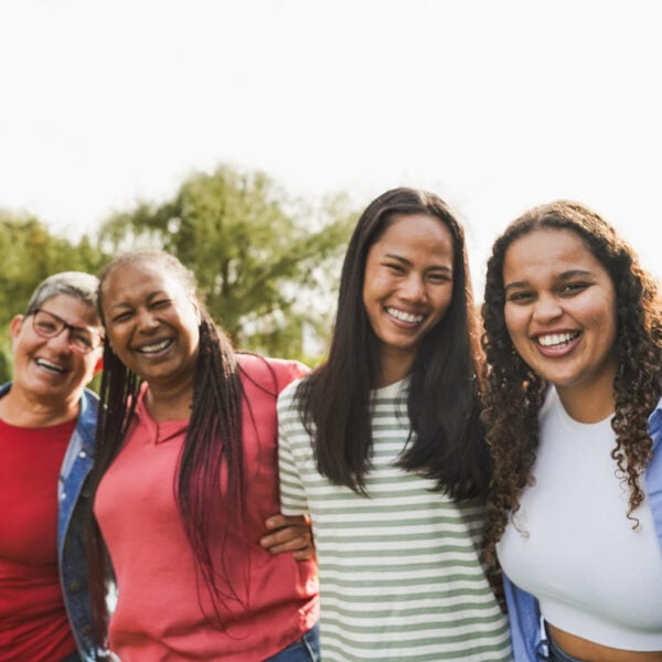 Multi generational women with arms around each other's shoulders together outdoors