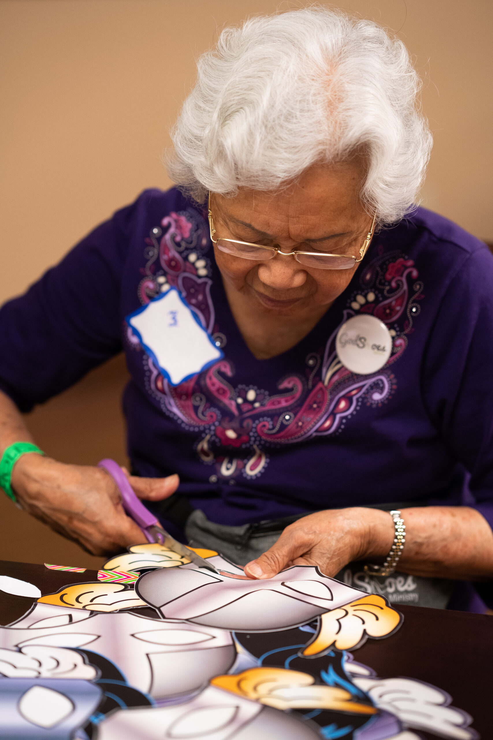 A 97-year-old volunteer cuts out photo-booth props at the New Hope for Kids center.