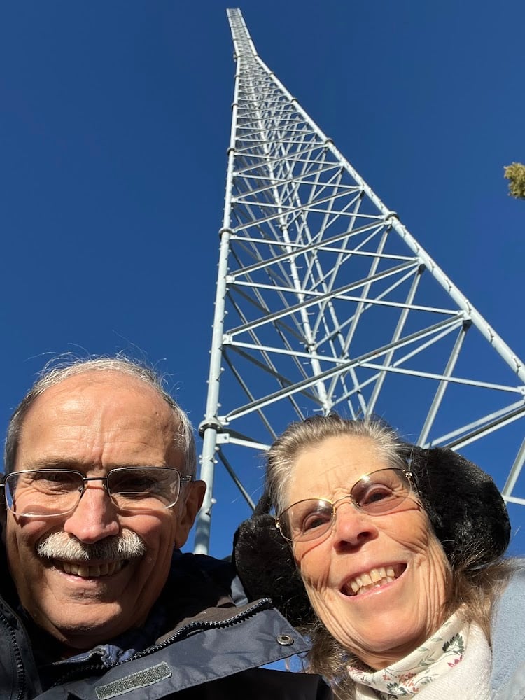 Two older people with radio tower in background