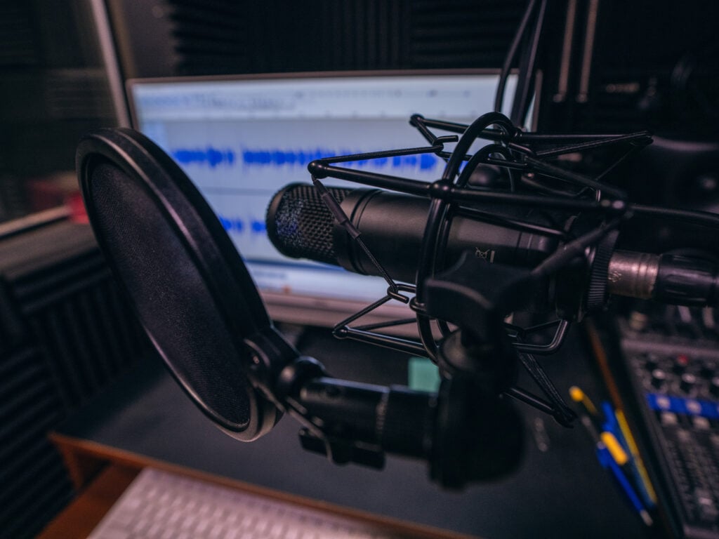 Close up of radio station microphone, mixer, computer, sound board