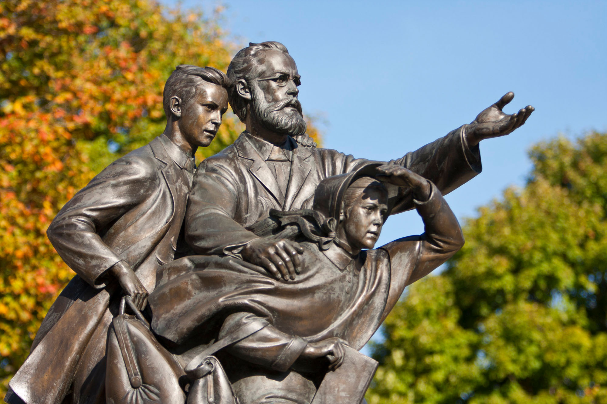 Photo of a bronze statute of a man and two children from the 1800s looking forward