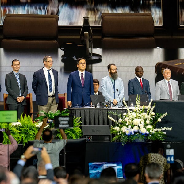 A diverse group of men in suits stand on a stage