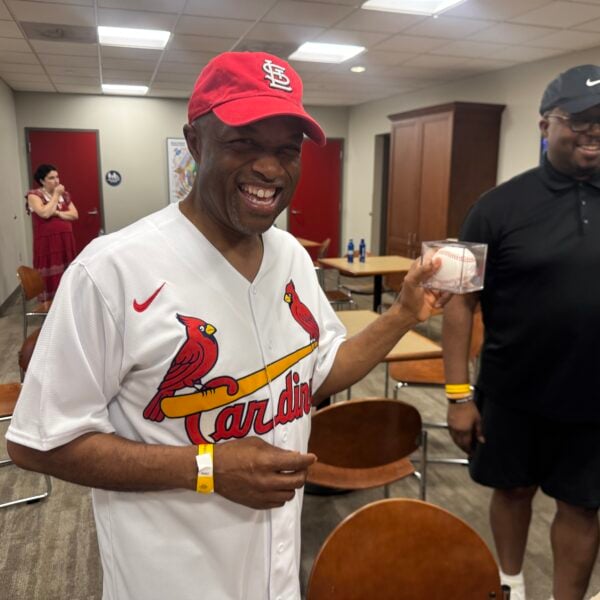 Middle age Black man in Cardinals shirt with baseball smiles