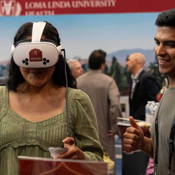 A young woman wears a VR headset as a young man looks on