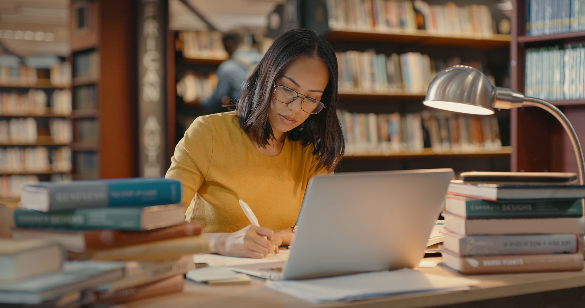 Young women at a table in a library doing research.