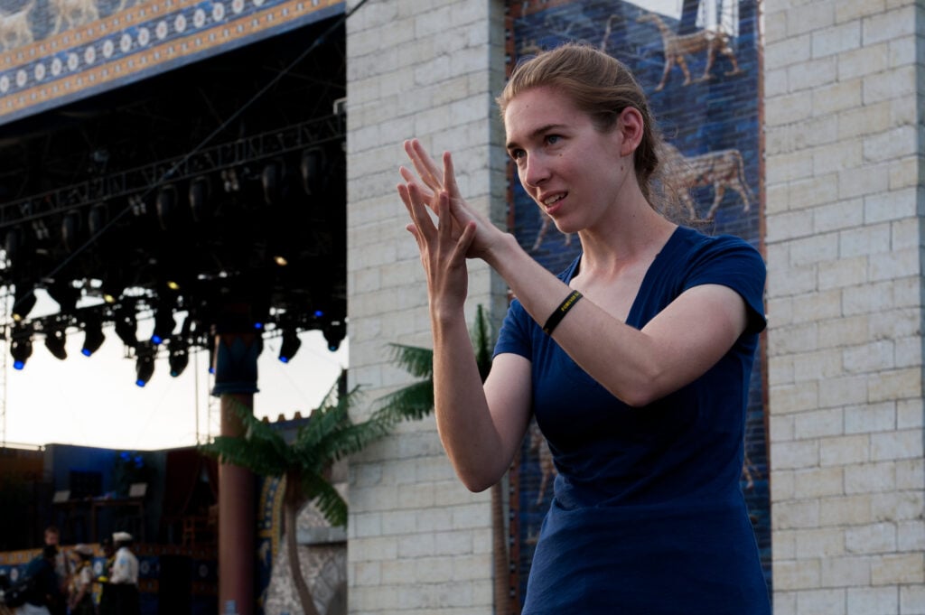 Girl providing sign language translation at a large outdoor event.