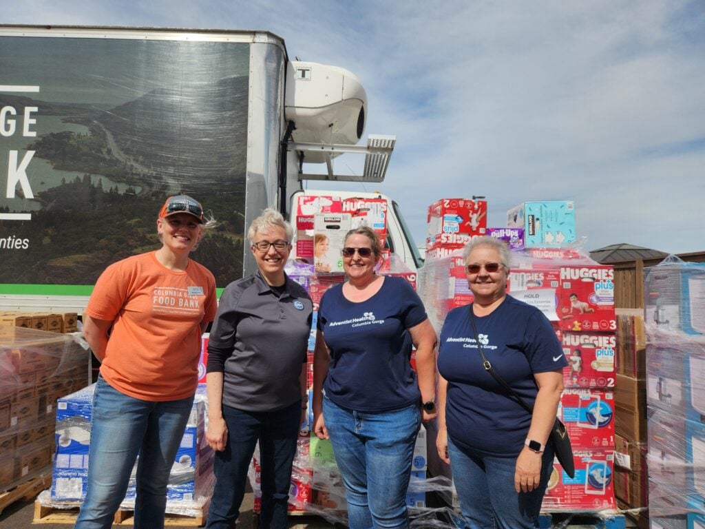 Volunteers stand in front of donations at distribution center.