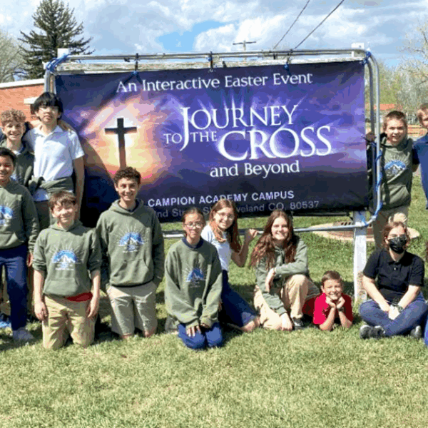 A photo of students in front of a sign reading "Journey to the Cross."