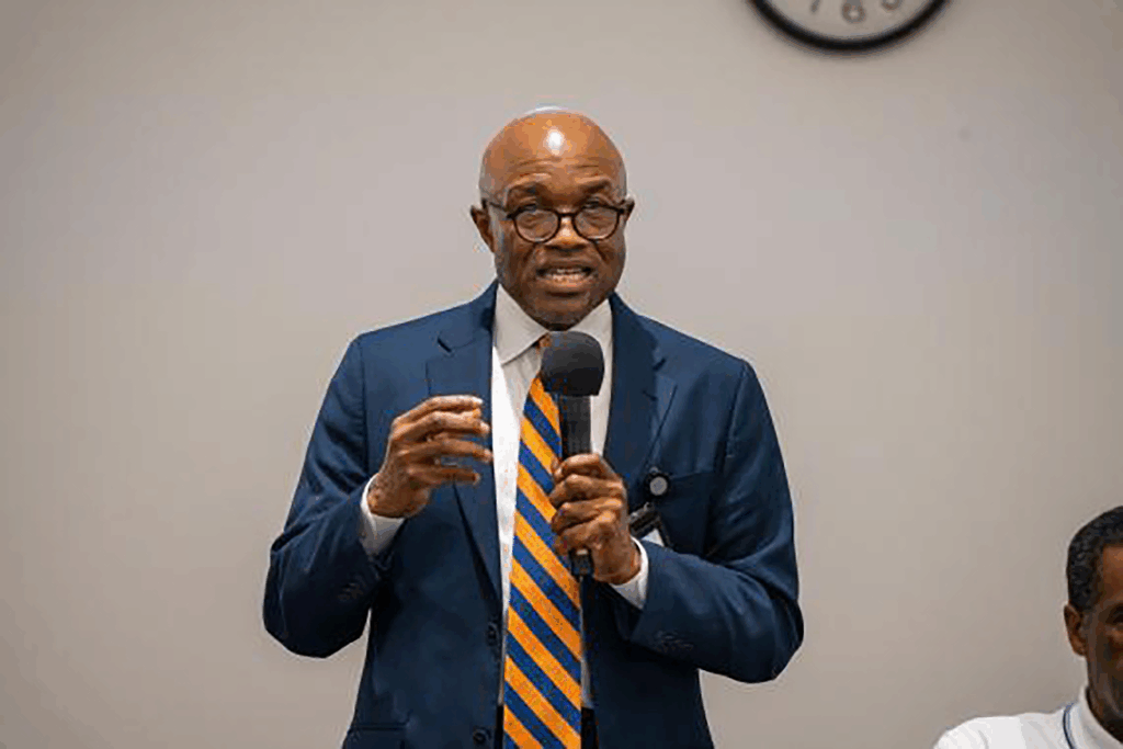 Black man speaking in front of a crowd