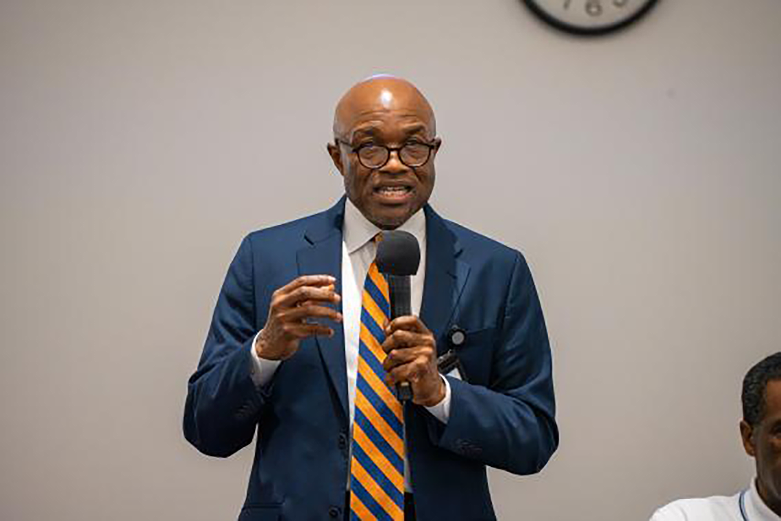Black man speaking in front of a crowd