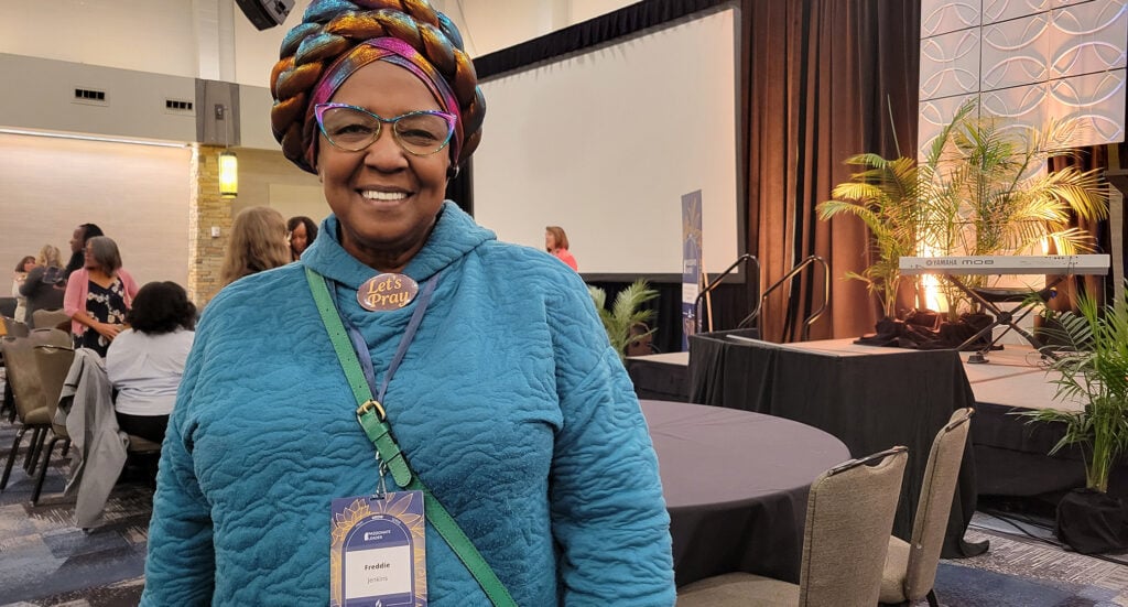 Smiling Black woman wearing a conference badge