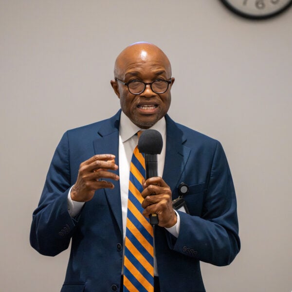 Black man speaks in front of an unseen crowd