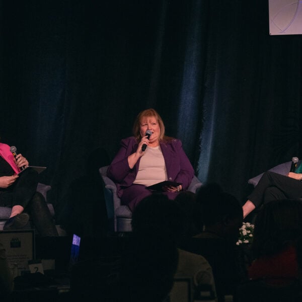 Three women sit together on a stage.