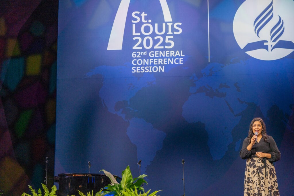 Hispanic woman singing on a stage with GC Session logo behind her.