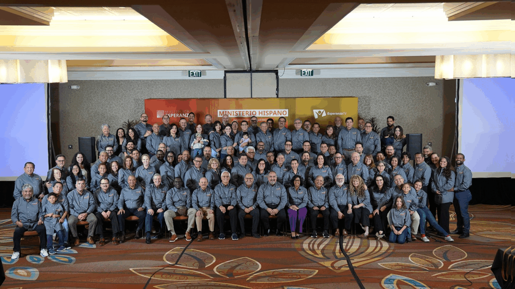 A picture of a large group and men and women in similar denim blue collared shirts. 