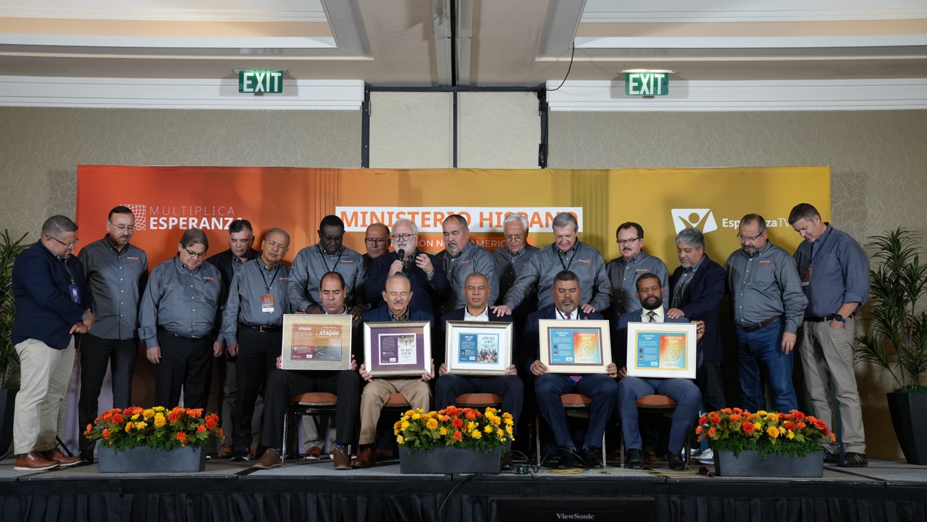 Photo of men posing with certificates on a stage.