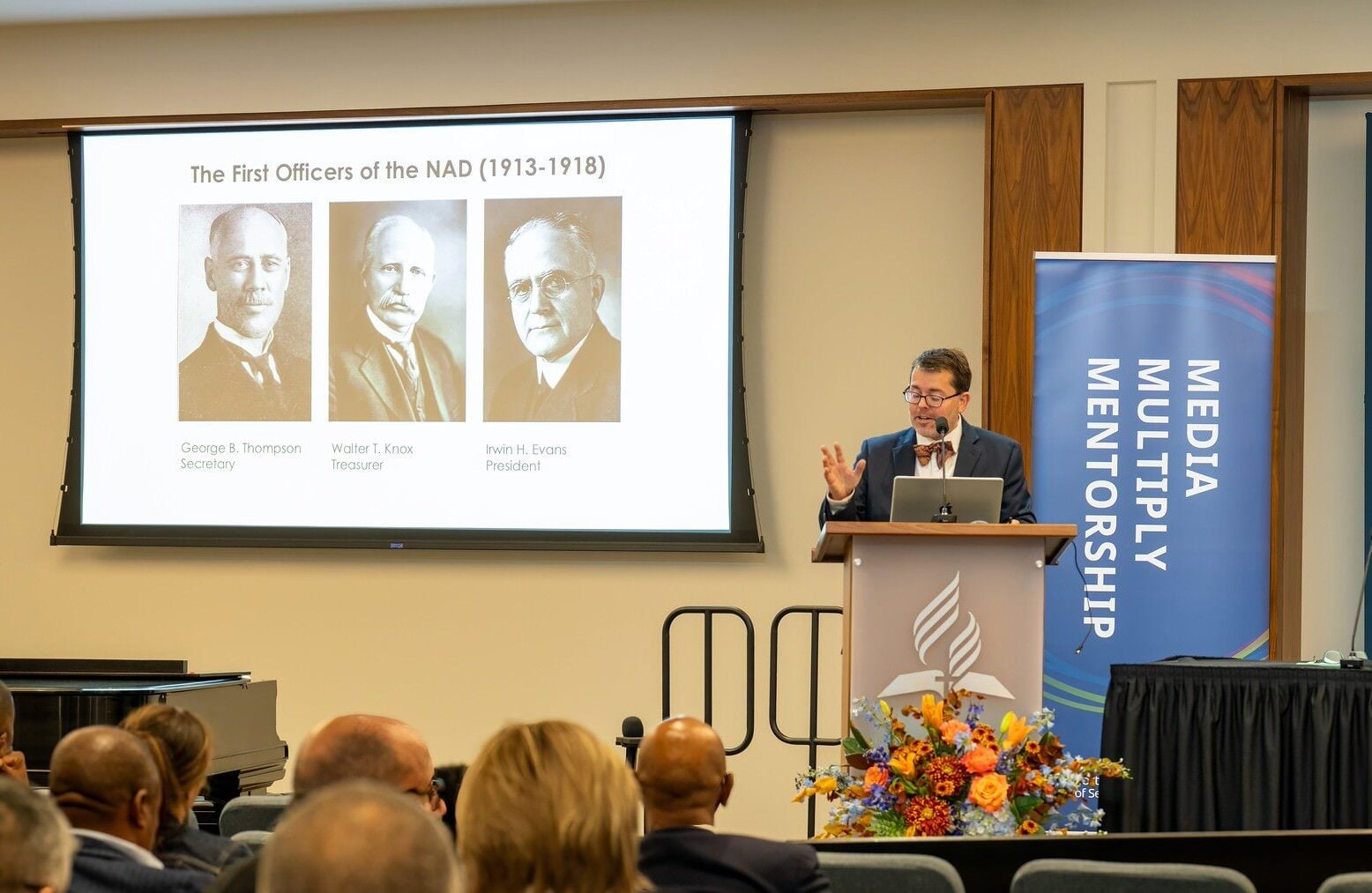 Man giving a powerpoint presentation to conference attendees.