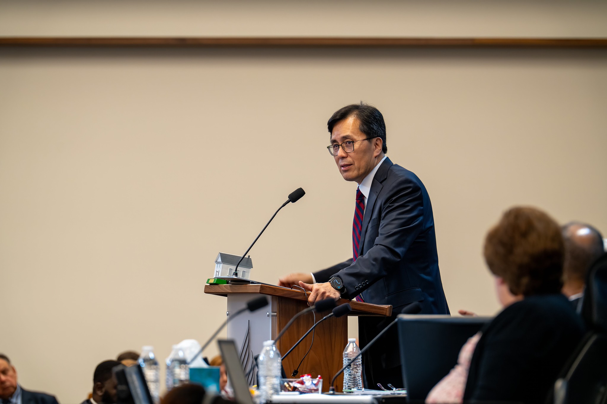 Middle age Asian man stands at a microphone during meetings at the North American Division auditorium.