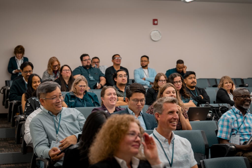 People in a classroom setting laugh at something an unseen speaker has said