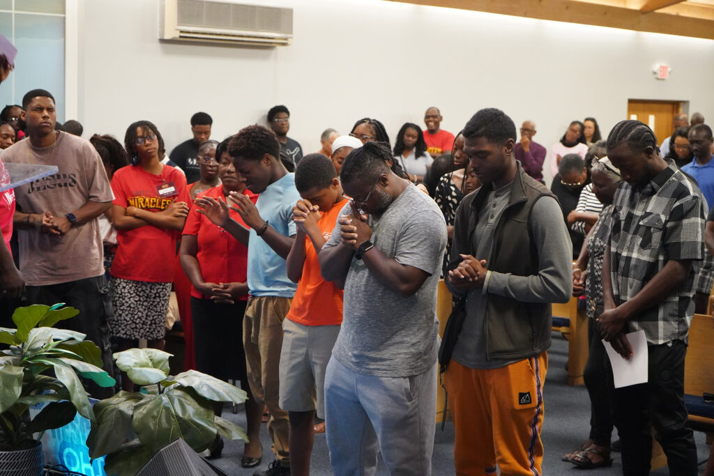 People stand up in sanctuary with eyes closed and arms outstretched