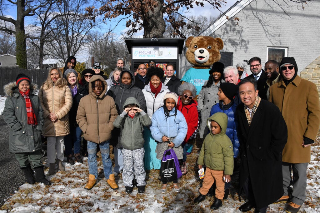 A group stands in front of a new community food pantry cupboard. 