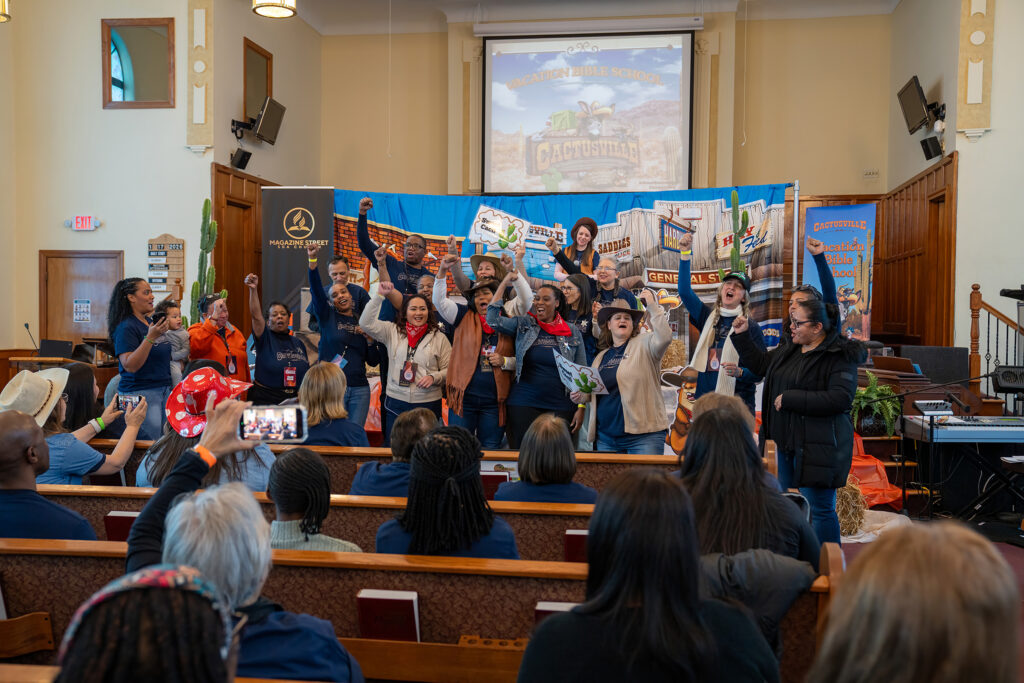 A group of men and women in a sanctuary in front of a colorful backdrop, pumping their fists.
