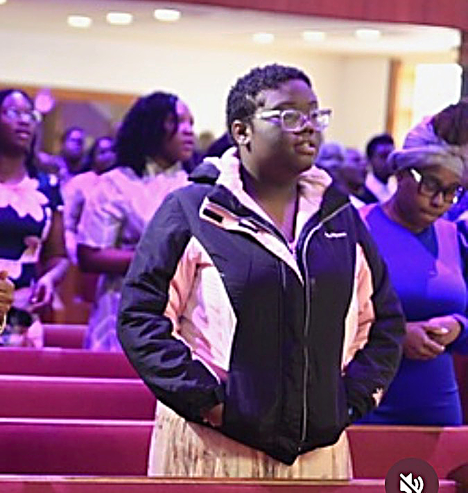 Young adult woman standing up in church enjoying the service.