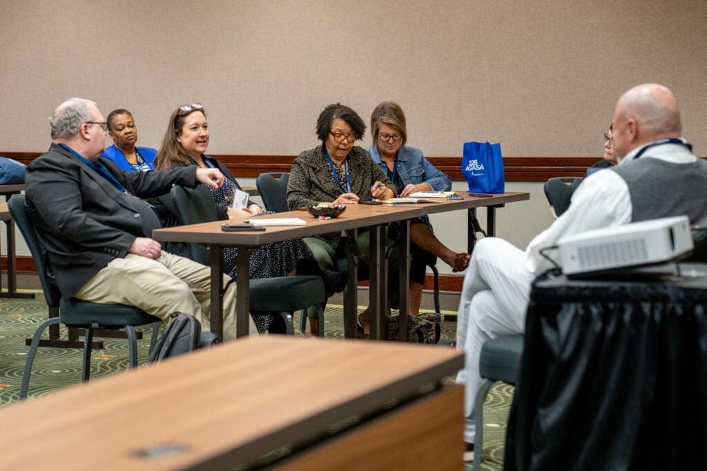 A group of people setting in a room having a discussion.