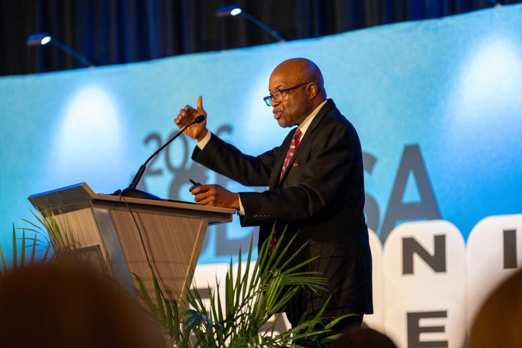 A male standing behind a podium speaking to an audience.