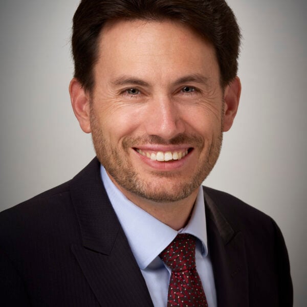 Caucasian man with dark hair wearing a suit and tie