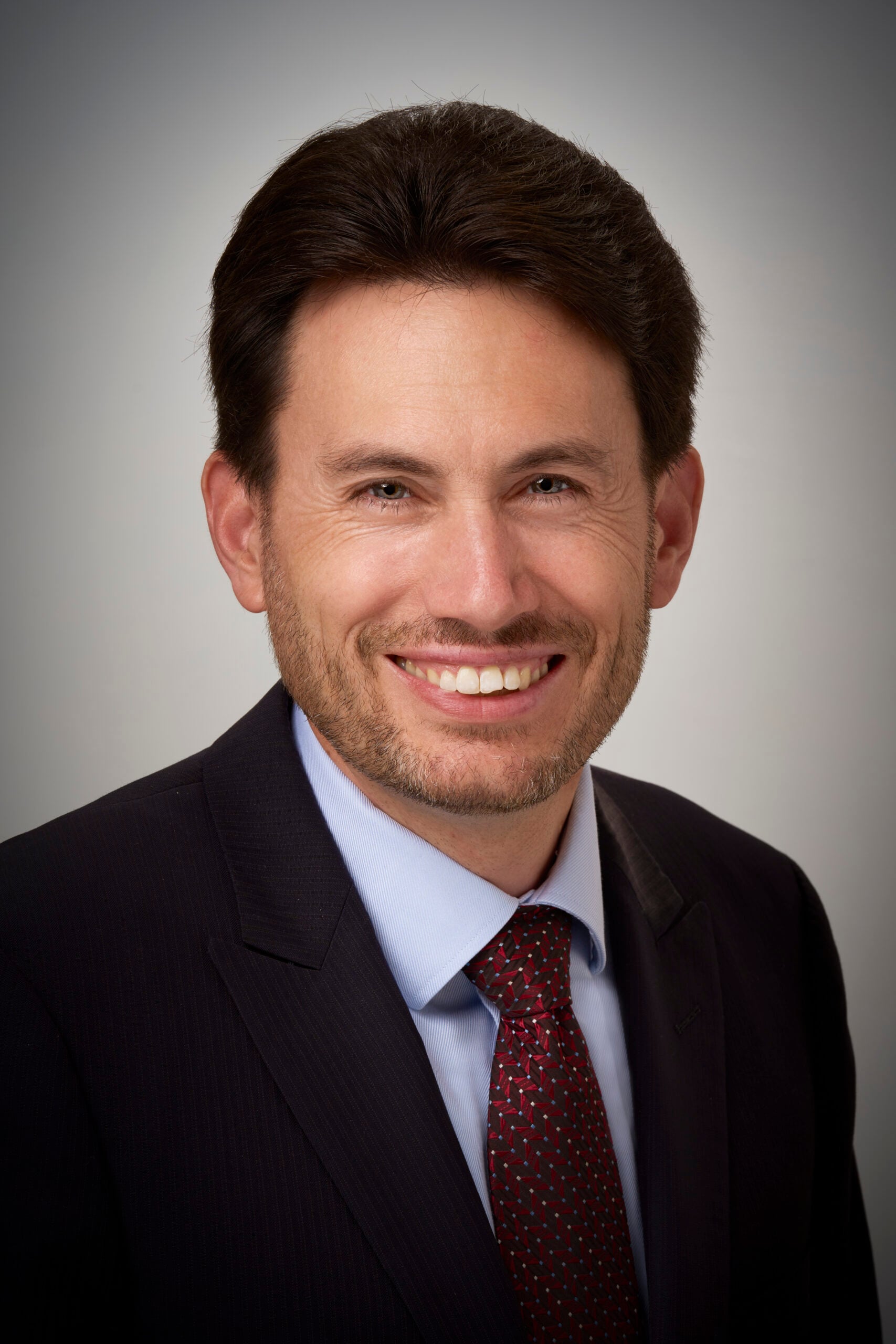 Caucasian man with dark hair wearing a suit and tie