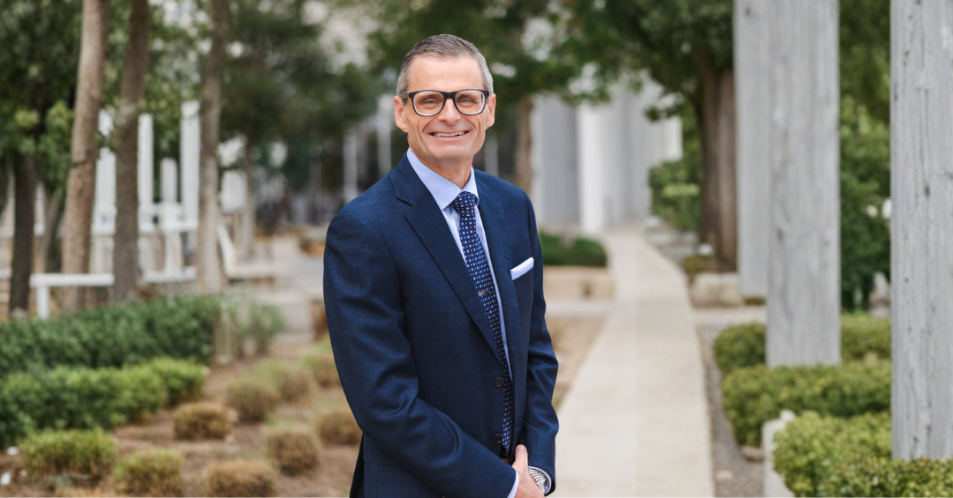 Middle aged caucasian man portrait outside on sidewalk with greenery around