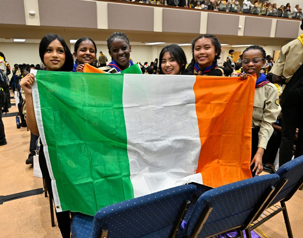 Several young women hold a large Irish flag on the Pathfinder Bible Experience testing floor. 