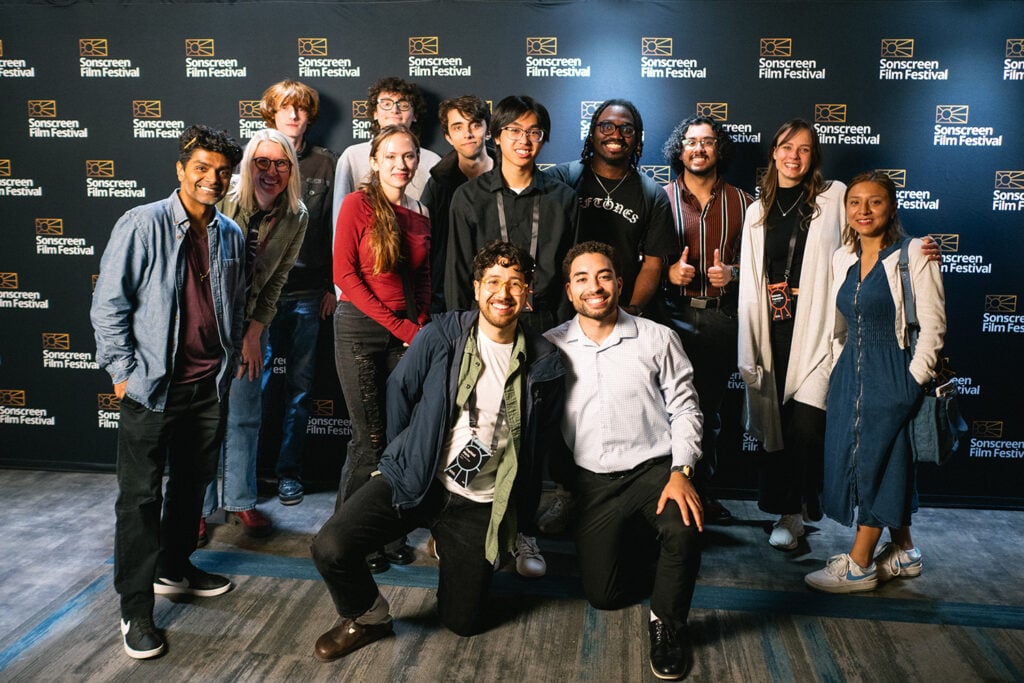 Group of college students posing in front of a film festival step-and-repeat backdrop