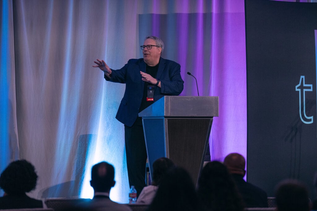A man speaks in an animated way at a podium