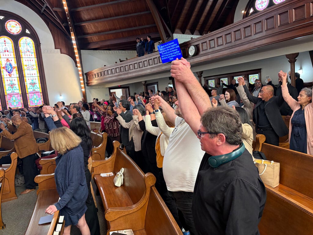 People stand and join hands in a sanctuary