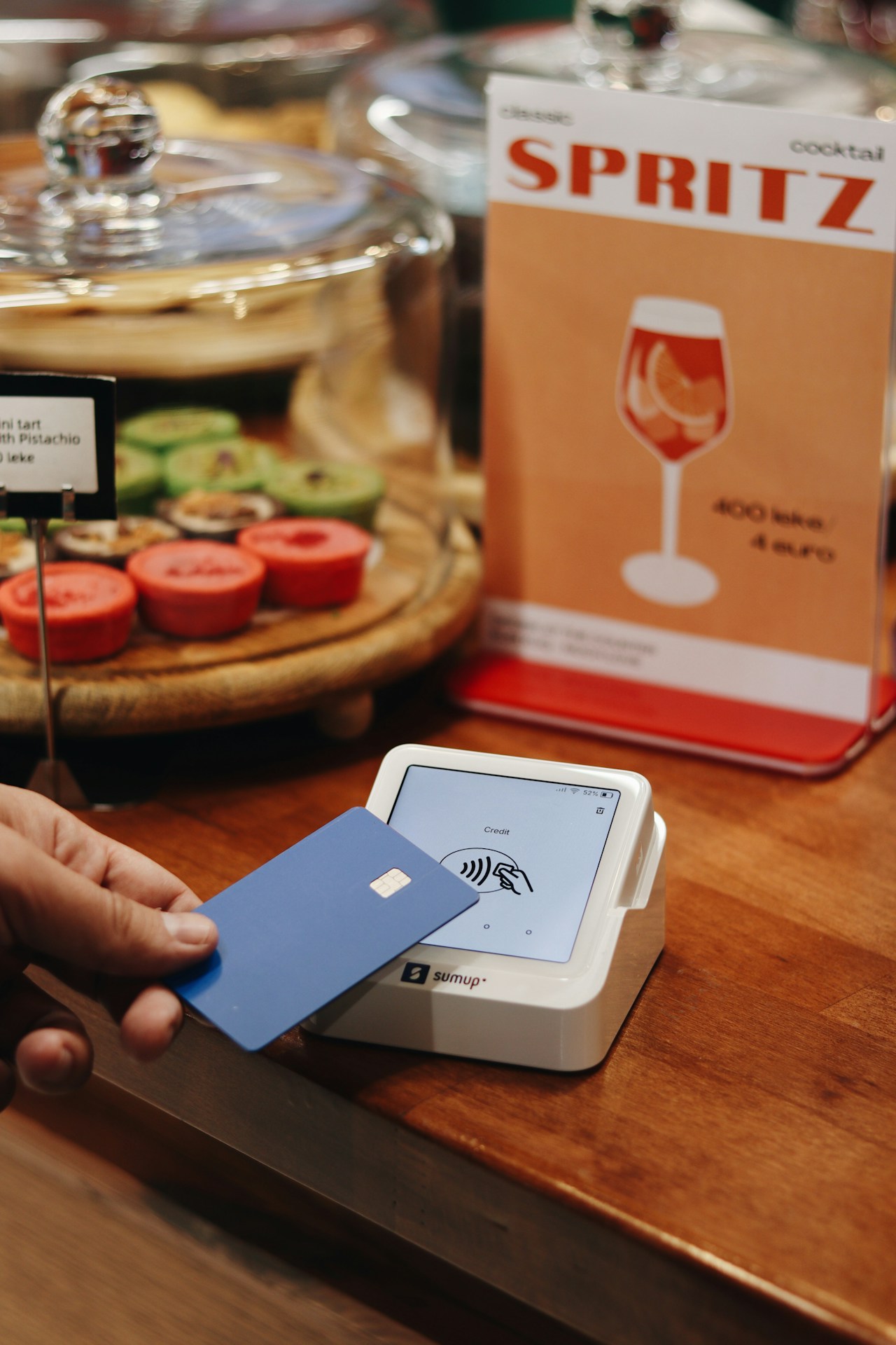 A person holding a card in front of a display of wine glasses