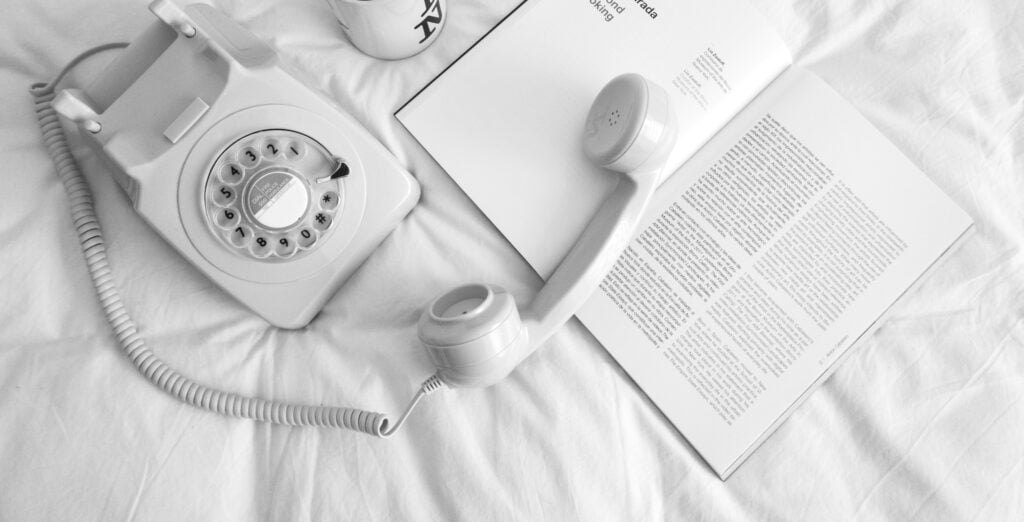 white rotary phone beside white ceramic mug