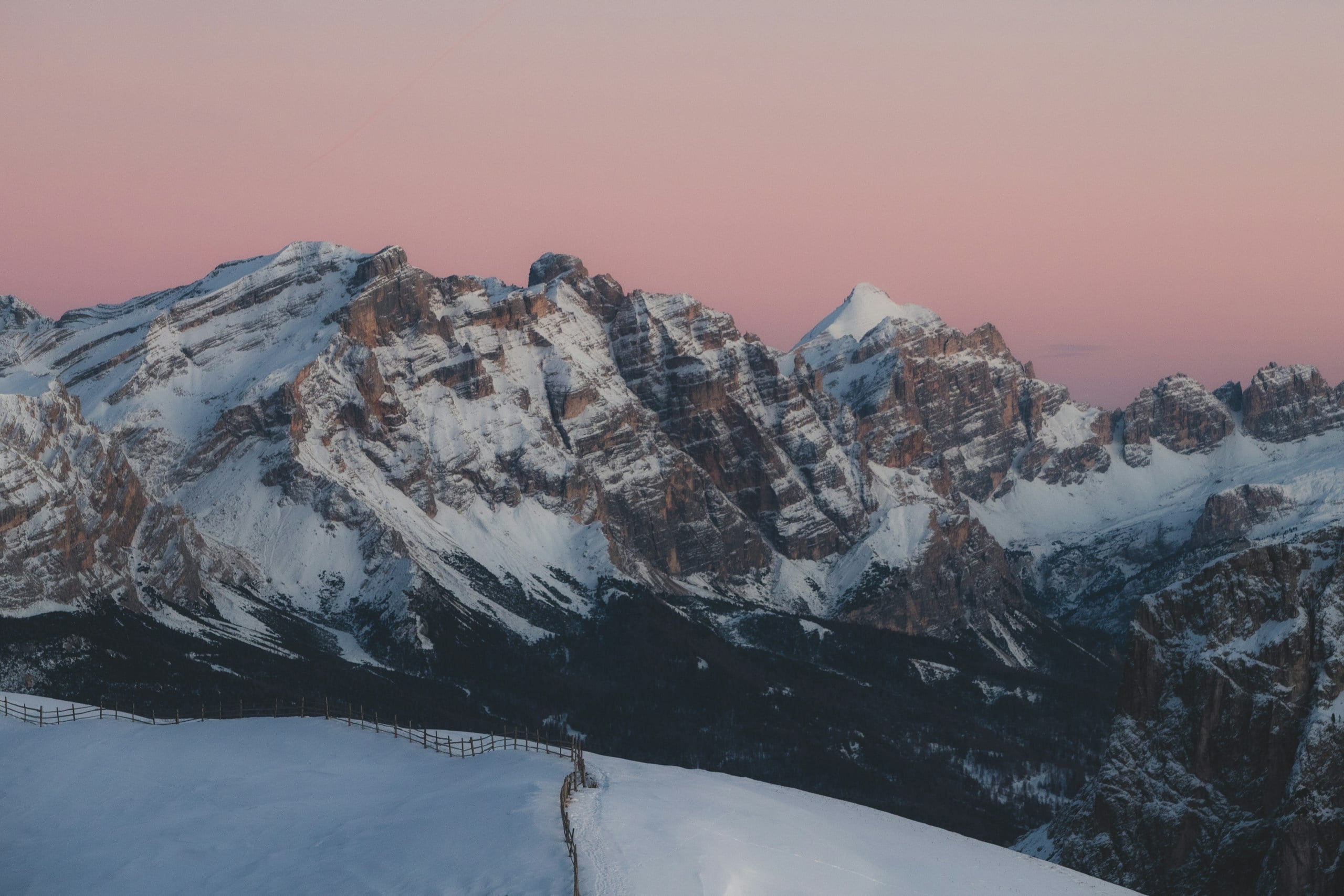 Snow-covered mountains under a pink sky.