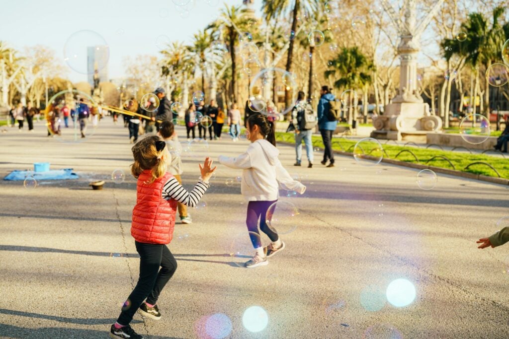 Children chasing bubbles in a sunny park.