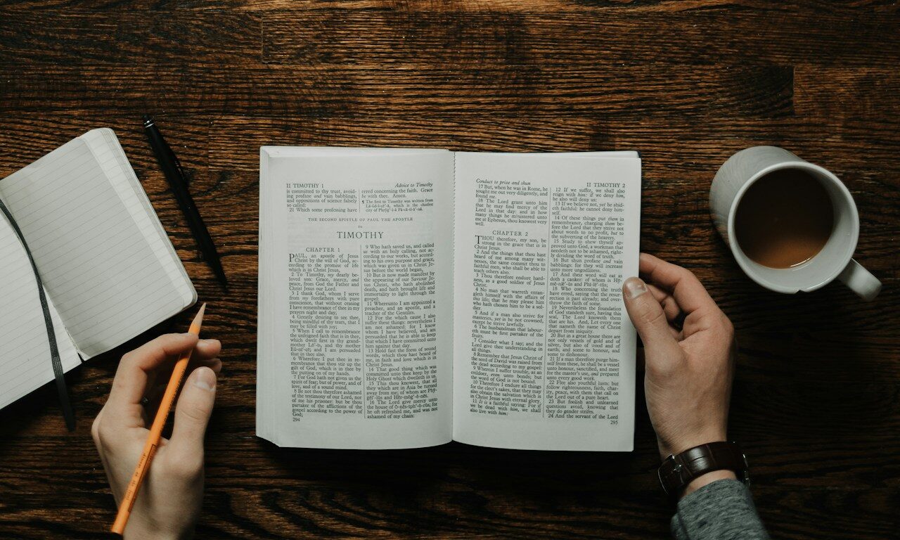 person sitting by the table opening book