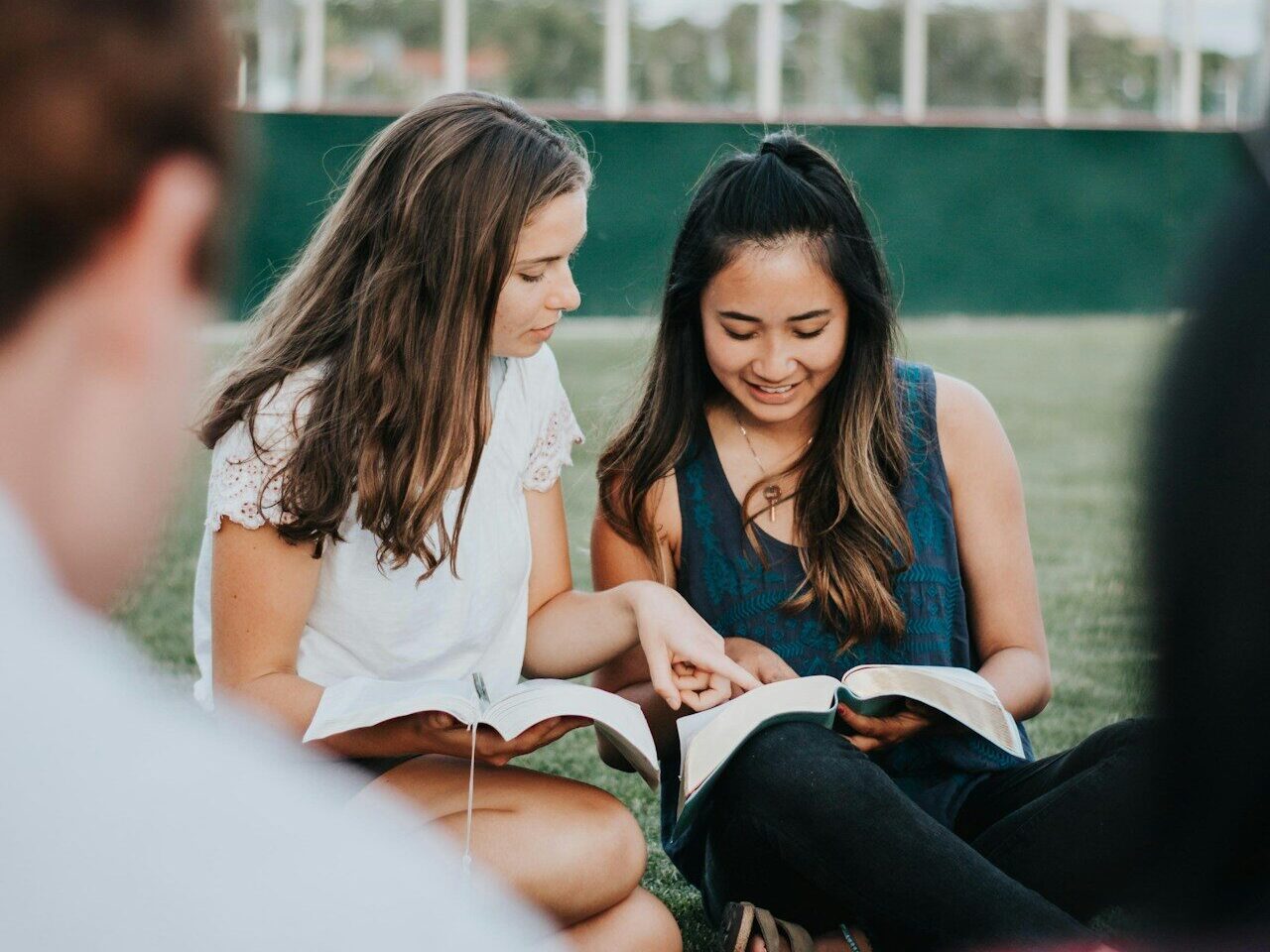 a group of people sitting on the ground looking at a book